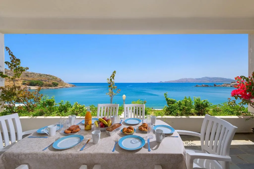 Ein Frühstückstisch auf einem schattigen Balkon mit Blick auf eine türkisfarbene Bucht