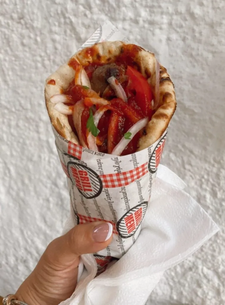 Ein in Papier gewickeltes Souvlaki vor einer weißen Wand
